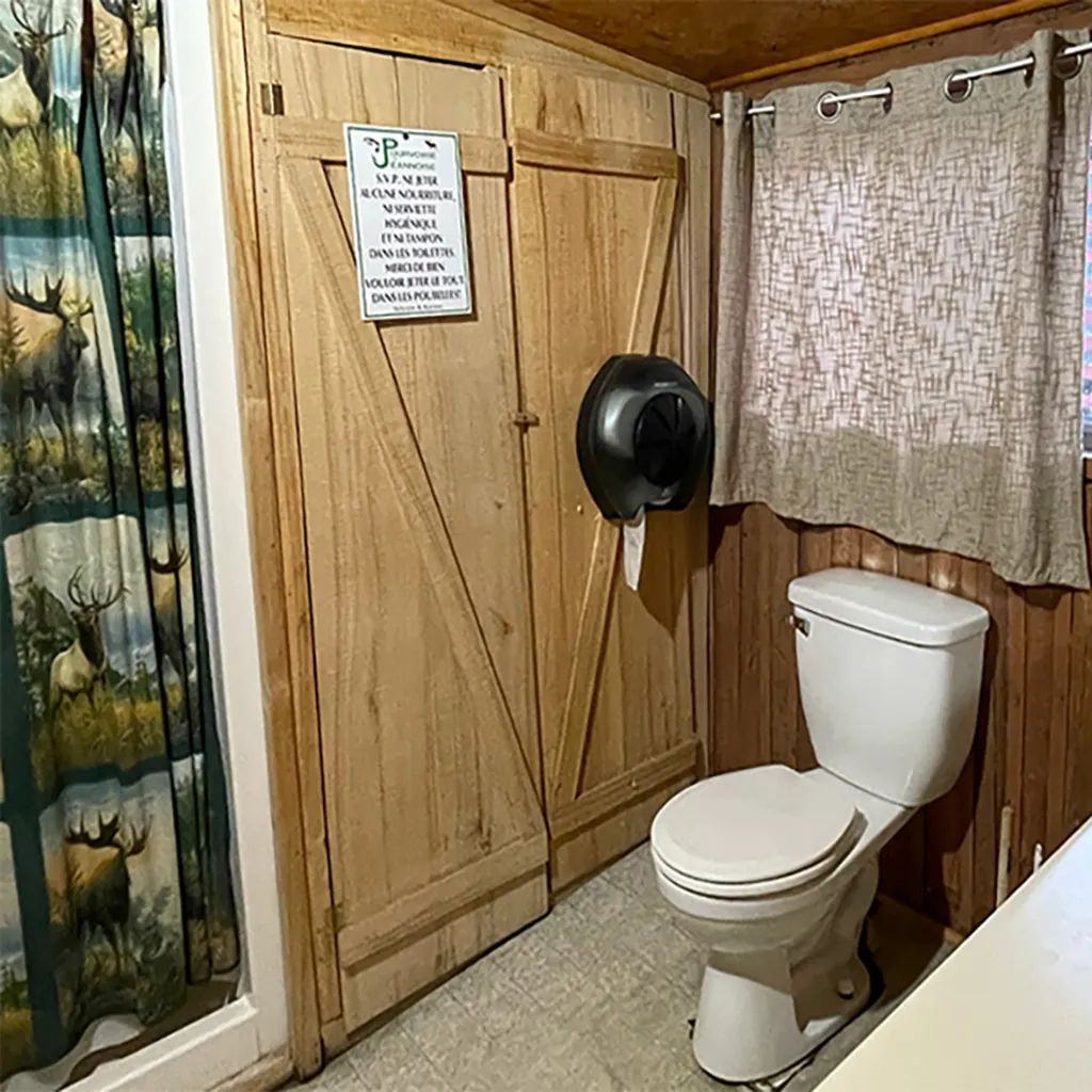 Vue de la salle de bain du chalet avec ses murs en bois et sa décoration rustique.