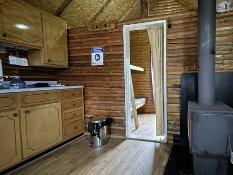 View of the kitchen area and wood stove inside the cabin.