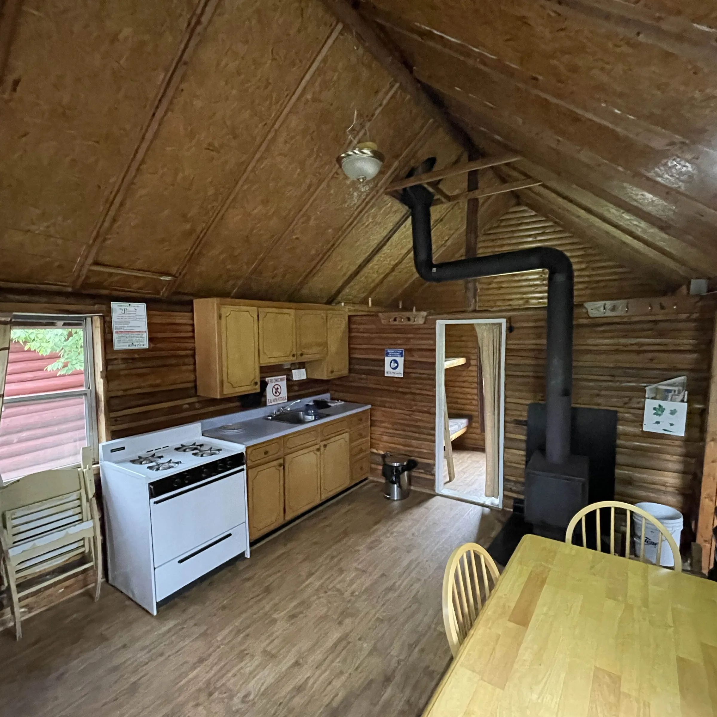 The cabin's kitchen and dining area include a stove and a wood-burning stove.
