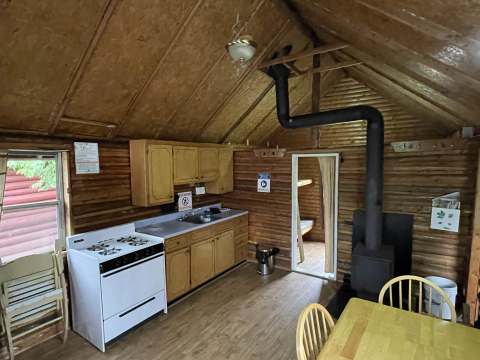 The cabin's kitchen and dining area include a stove and a wood-burning stove.