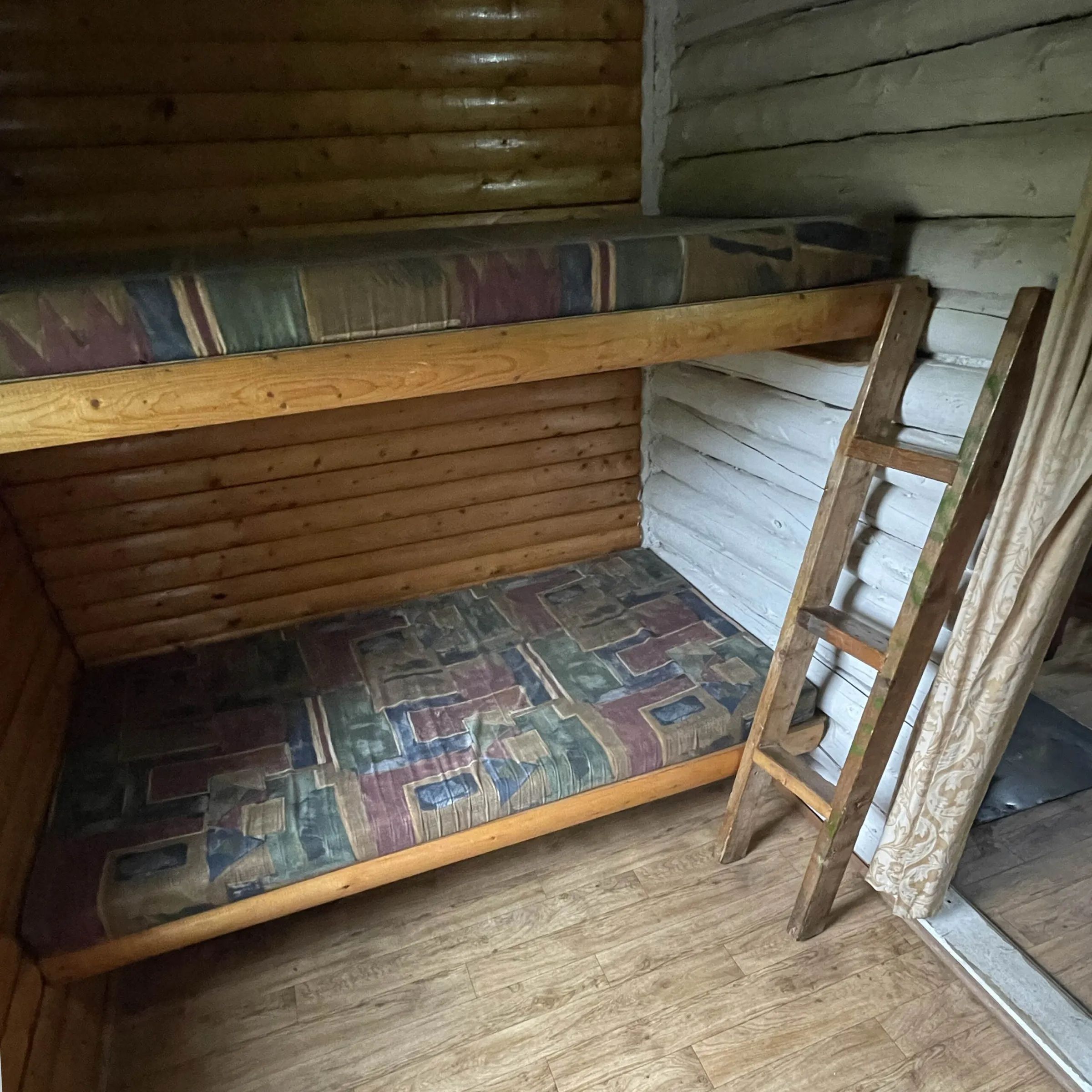 This cabin features wooden bunk beds with mattresses in the bedroom.