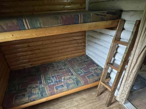 This cabin features wooden bunk beds with mattresses in the bedroom.