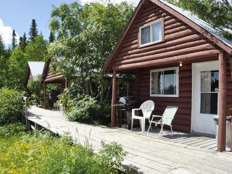 Side view of the log cabins with their outdoor terrace and barbecues.