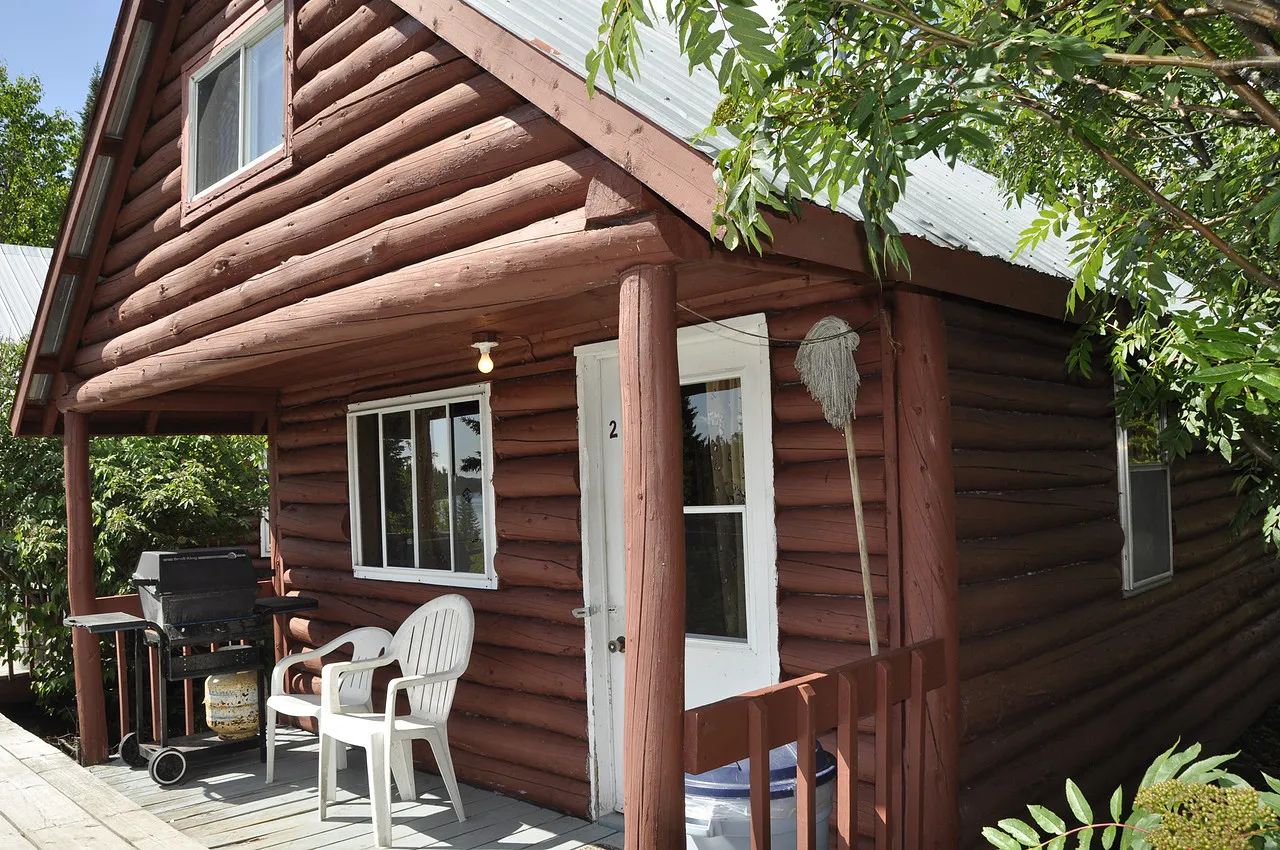 Exterior facade of cabin 2 with its porch, including chairs and a barbecue.