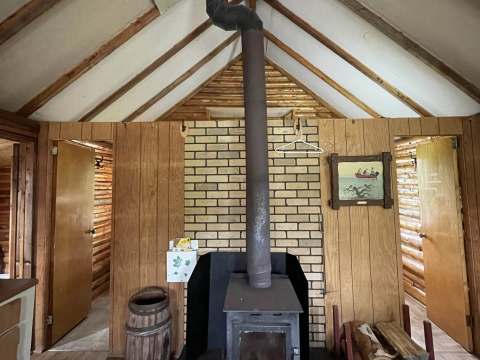 The cottage interior features a central wood stove and wood paneling on the walls.