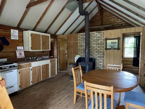 The open-concept kitchen and dining area of the cabin features a wood stove.