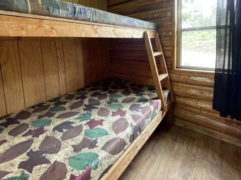 A wooden bunk bed is set up in the cabin to maximize sleeping space.