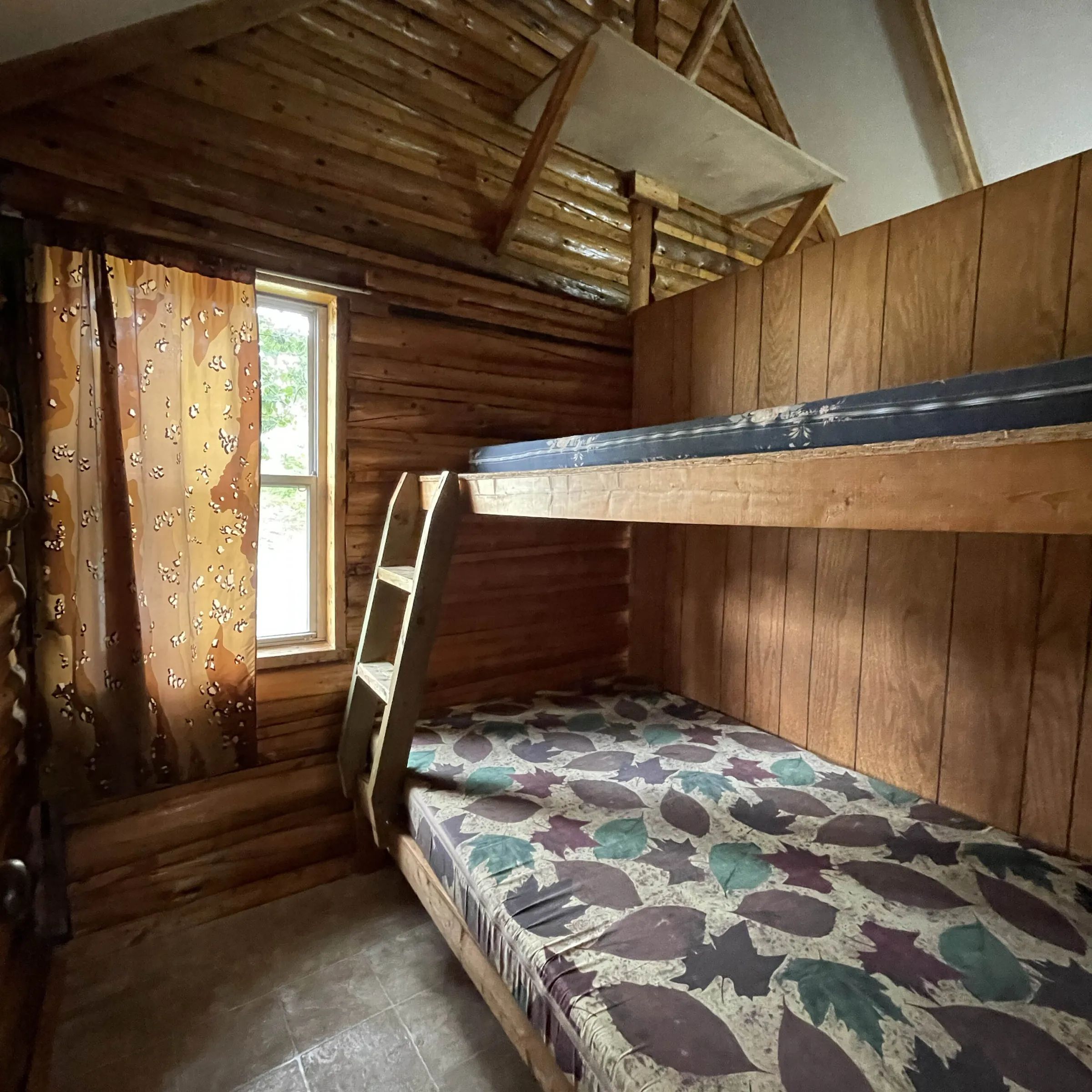 This rustic bedroom in cabin 2 features a wooden bunk bed.