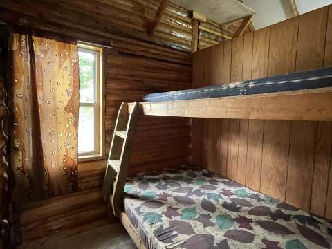 This rustic bedroom in cabin 2 features a wooden bunk bed.