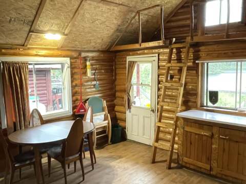 View of the main living area with dining table and ladder leading to the loft of chalet 3.