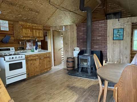 The cottage 3 kitchen includes a stove, a dining table, and a wood stove.