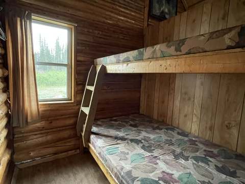 This rustic bedroom in chalet 3 is equipped with wooden bunk beds.
