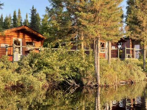 Vue sur les chalets en bois rond bordant le rivage du lac dans la lumière du soleil couchant.