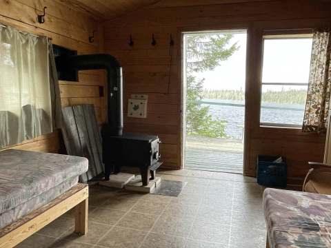 Vue intérieure du chalet avec son poêle à bois et son accès direct à la terrasse donnant sur le lac.