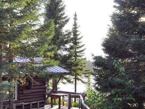 A wooden path leads to the outdoor deck of this log cabin.
