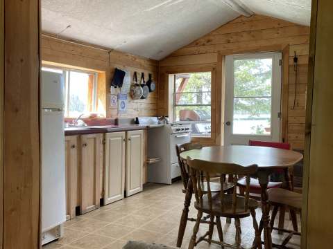 The cabin kitchen and dining area are equipped with a stove and a wooden table.