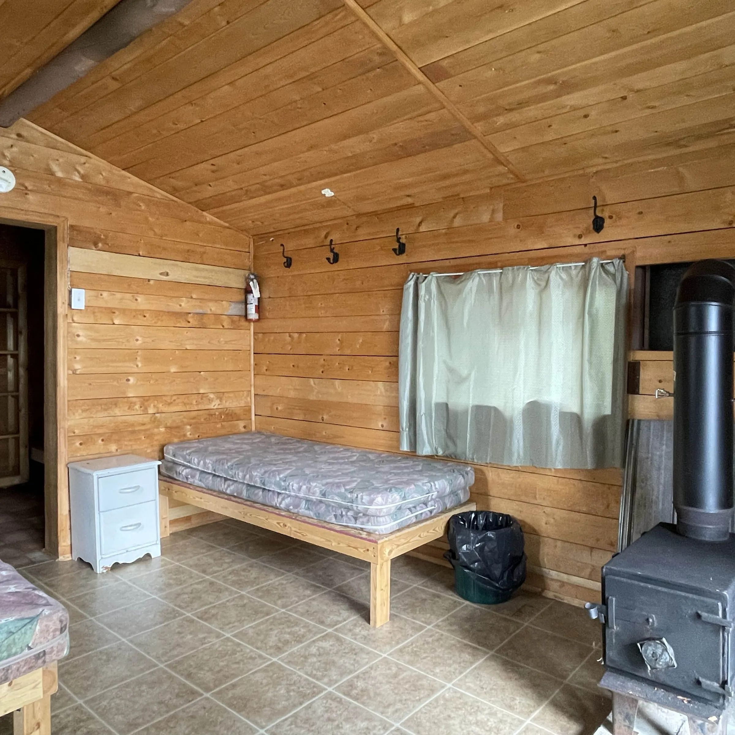 The interior of the cottage includes a single bed and a wood stove for your comfort.