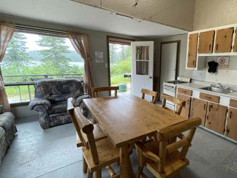 The cottage living area includes an equipped kitchen, a wooden dining table, and a lounge area.