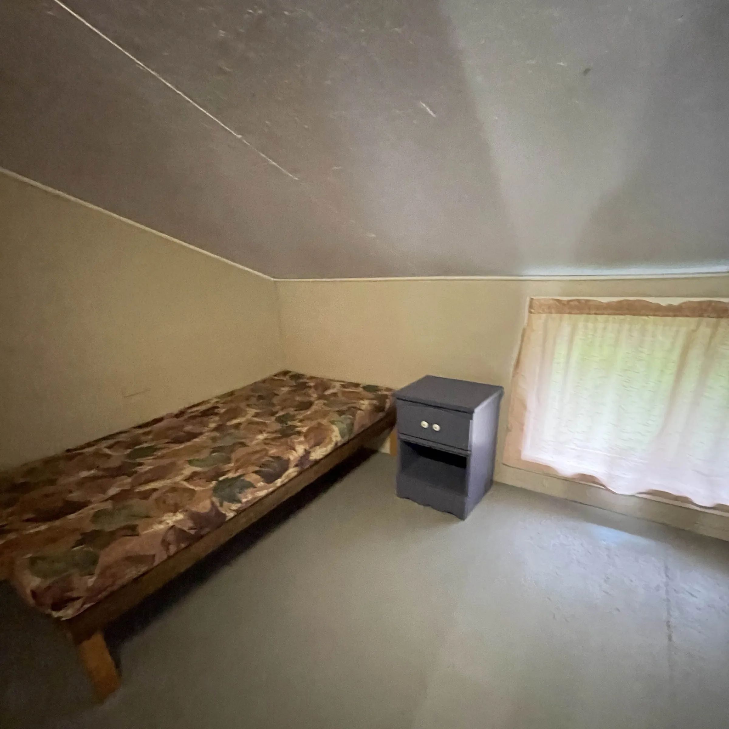 A bedroom with a camouflage-pattern single bed in chalet 7.