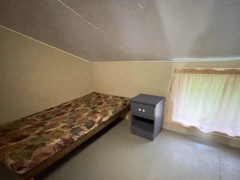 A bedroom with a camouflage-pattern single bed in chalet 7.