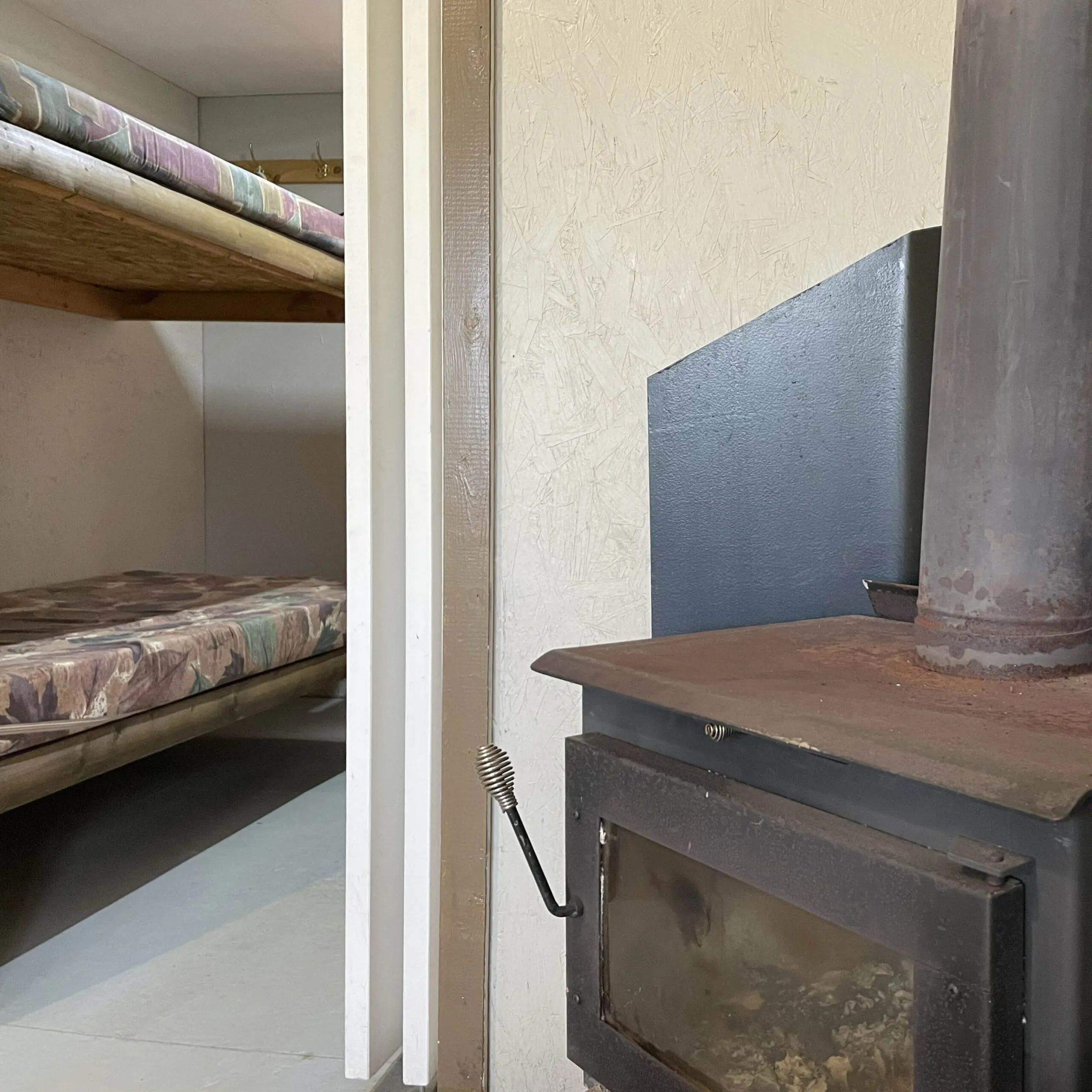 View of the wood stove and sleeping area with bunk beds in the cottage.