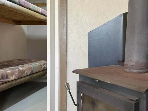 View of the wood stove and sleeping area with bunk beds in the cottage.