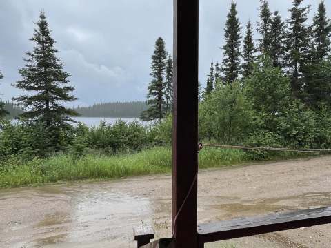 Vue sur la forêt et le lac depuis la galerie couverte du chalet.