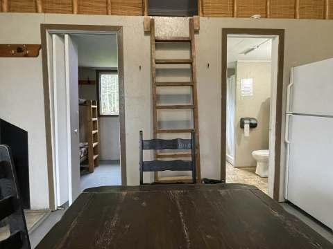 Vue de la table à manger dans le chalet avec accès aux chambres et à la salle de bain.