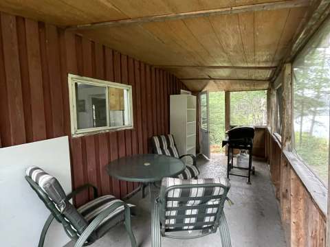 La galerie fermée du chalet Baribal dispose d'un espace de détente avec table, chaises et barbecue.