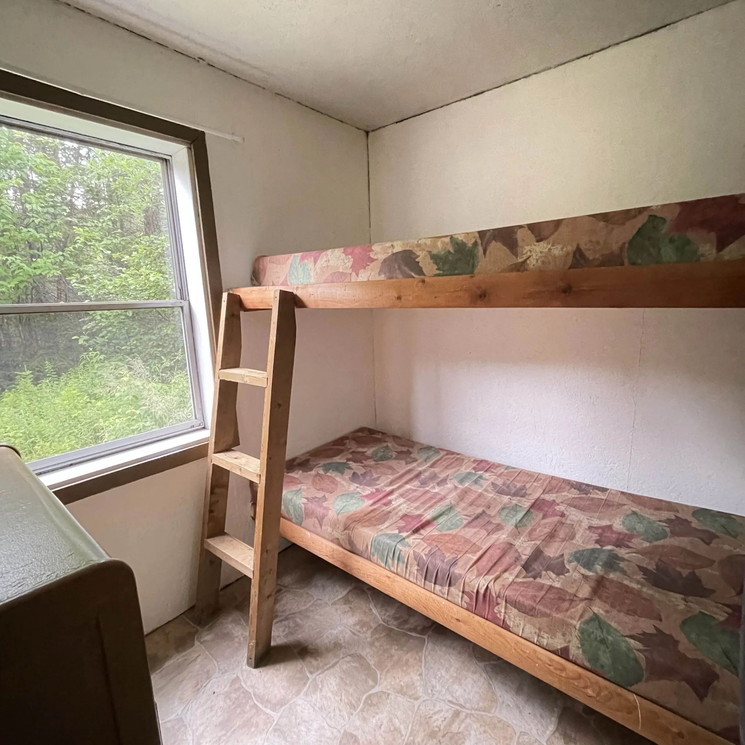 Cette chambre du chalet Baribal est équipée d'un lit superposé et d'une fenêtre donnant sur la forêt.