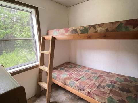 Cette chambre du chalet Baribal est équipée d'un lit superposé et d'une fenêtre donnant sur la forêt.