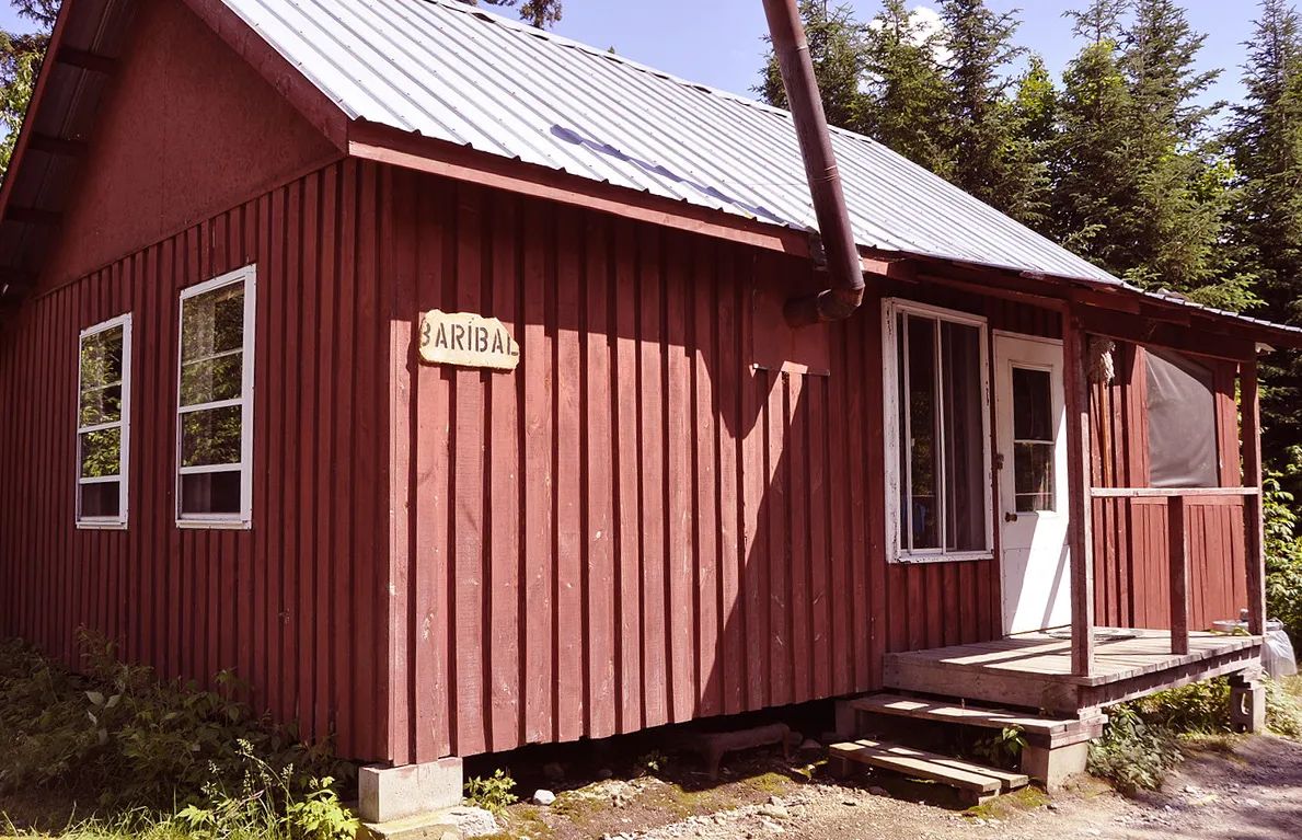 Vue extérieure du chalet Baribal avec son revêtement de bois rouge et sa galerie couverte.
