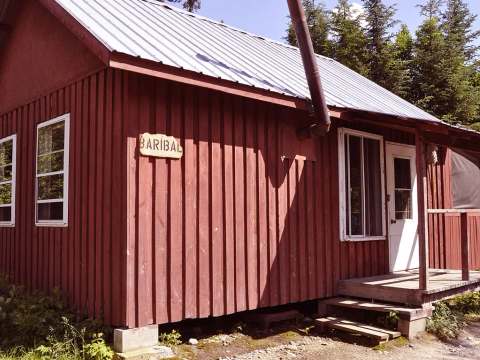Vue extérieure du chalet Baribal avec son revêtement de bois rouge et sa galerie couverte.