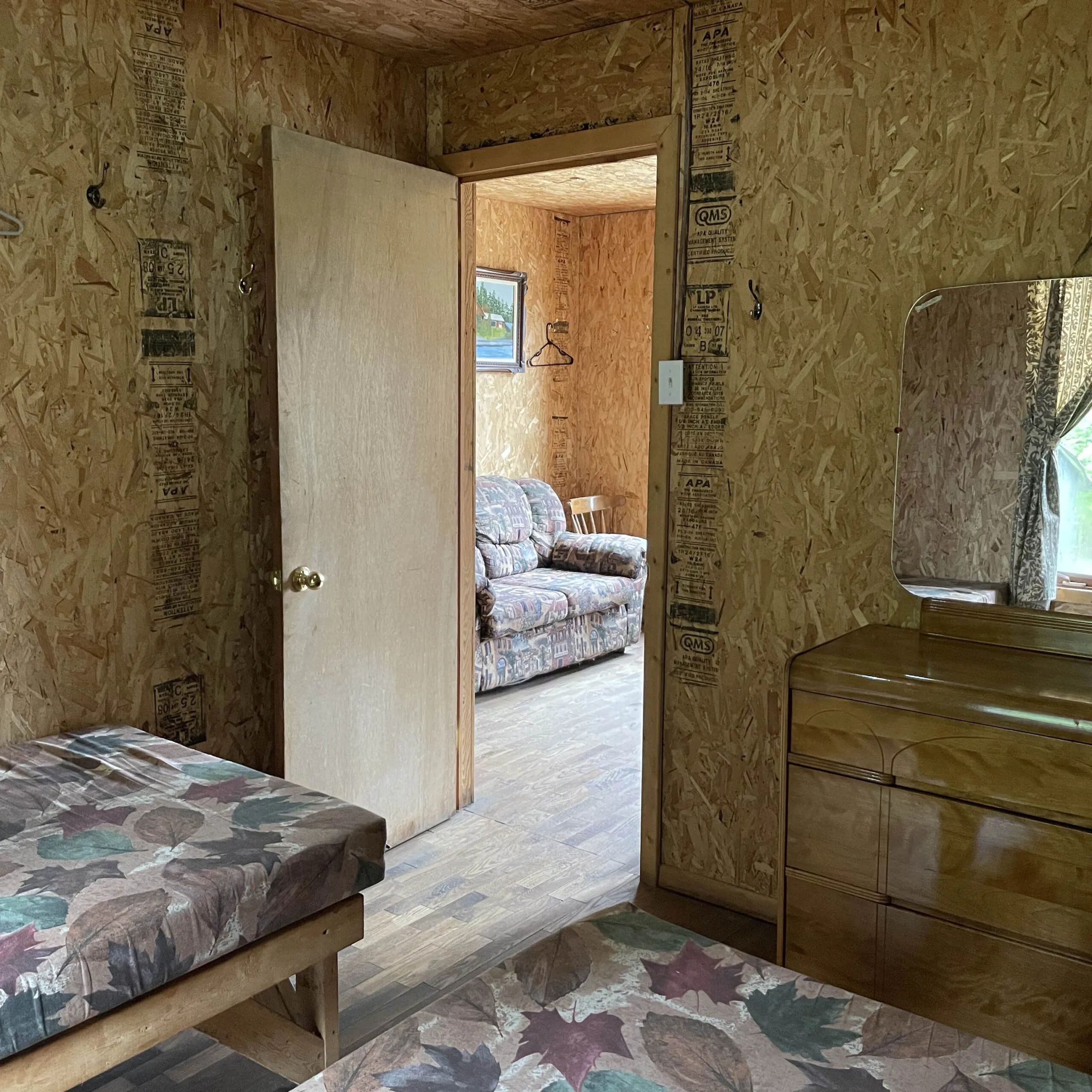 Vue intérieure des chambres communicantes du chalet avec murs en panneaux de copeaux orientés.