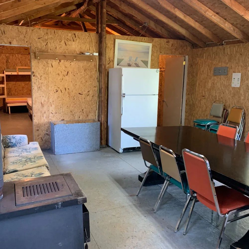 The open area of cabin 5 features a dining table, a seating area, and a refrigerator.