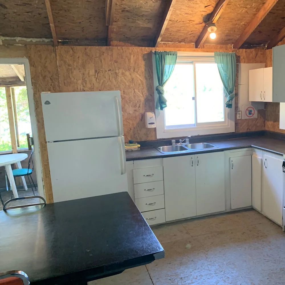 The equipped kitchen of chalet 5 features a refrigerator, a sink, and functional counter space.