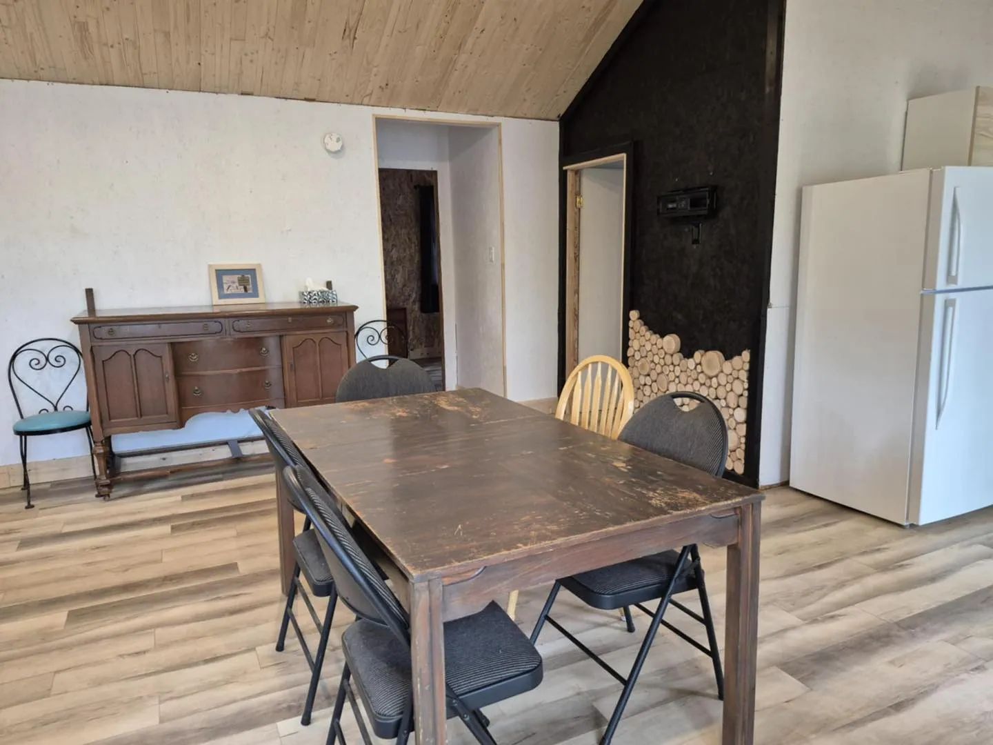 View of the dining area in cottage 7 with a wooden table and a refrigerator.