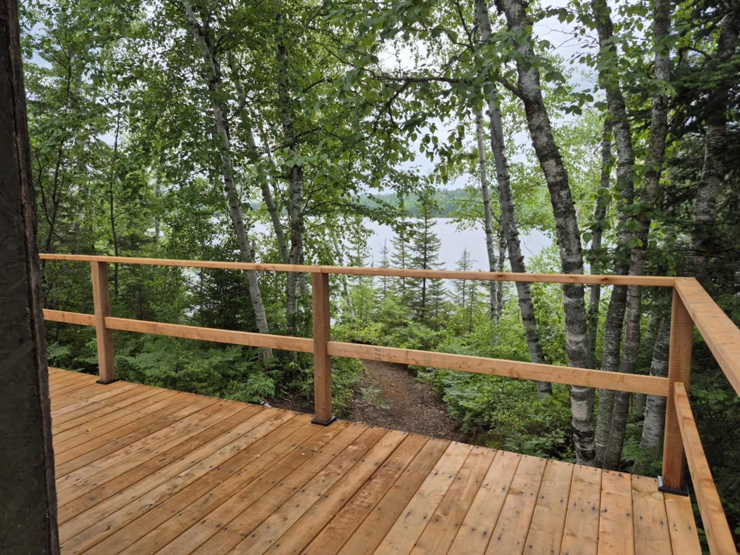 View of the forest and lake from the wooden deck of cottage 7.