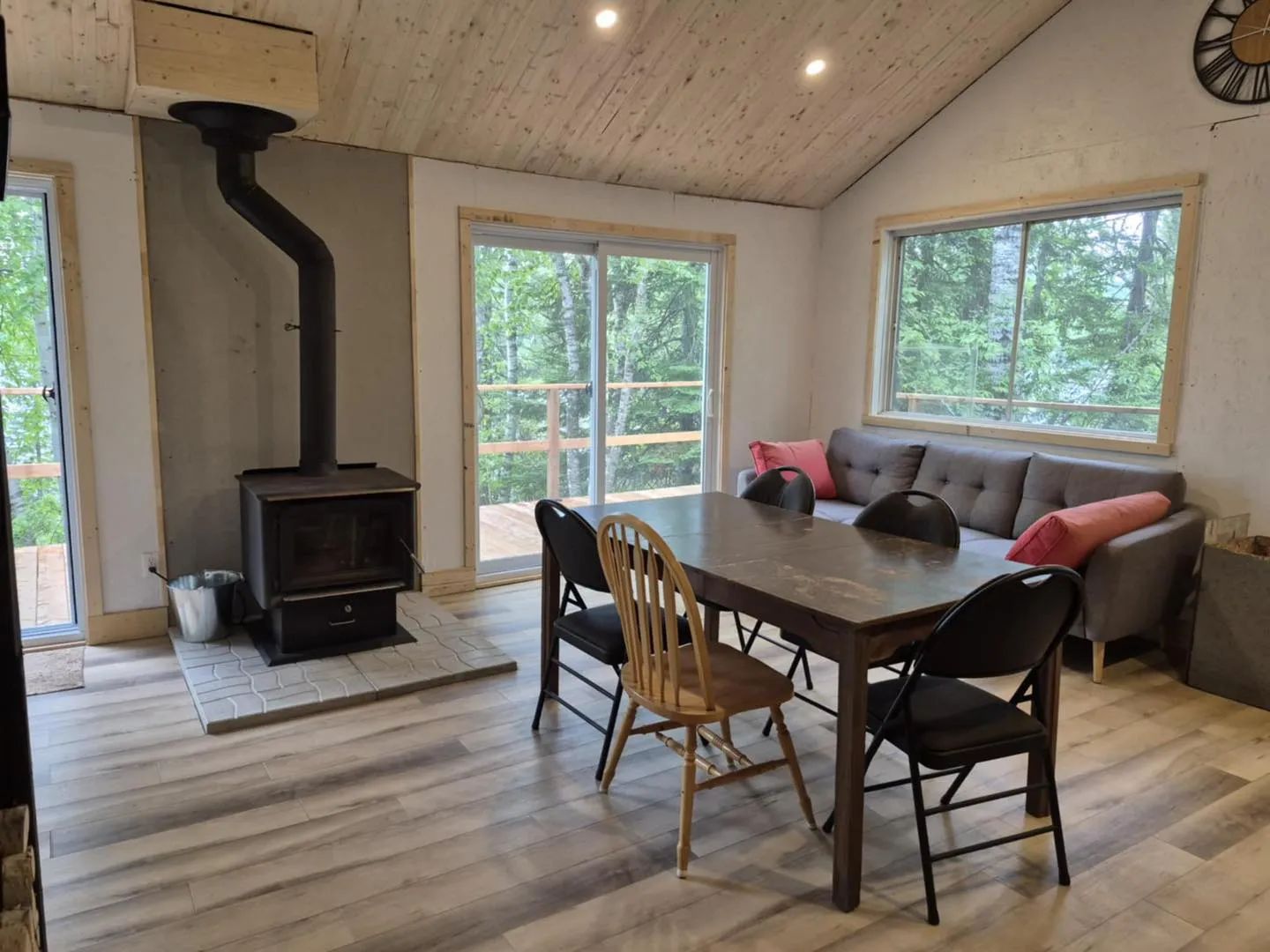The chalet's open area features a dining table, a comfortable living room, and a wood stove.