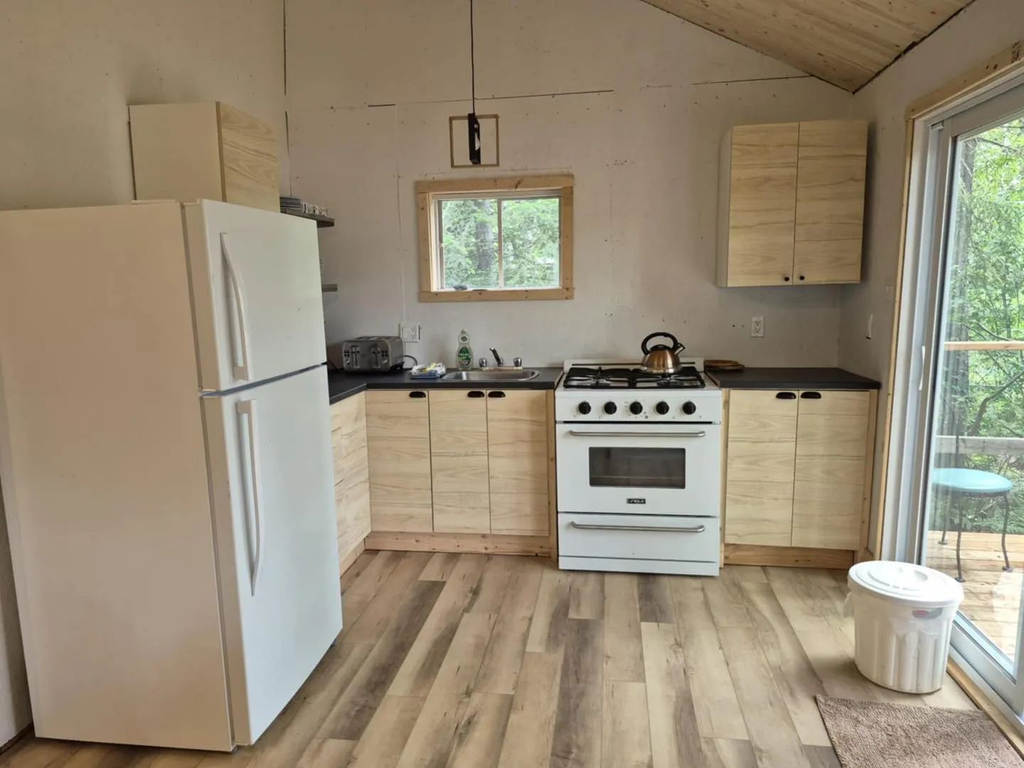 The kitchen in cottage 7 is equipped with a refrigerator, a stove, and storage space.