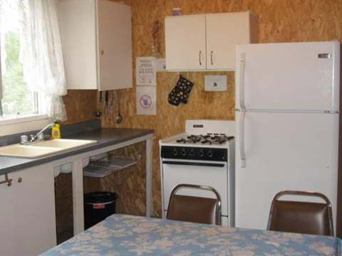 The cottage's functional kitchen includes a stove, a refrigerator, and a dining area.