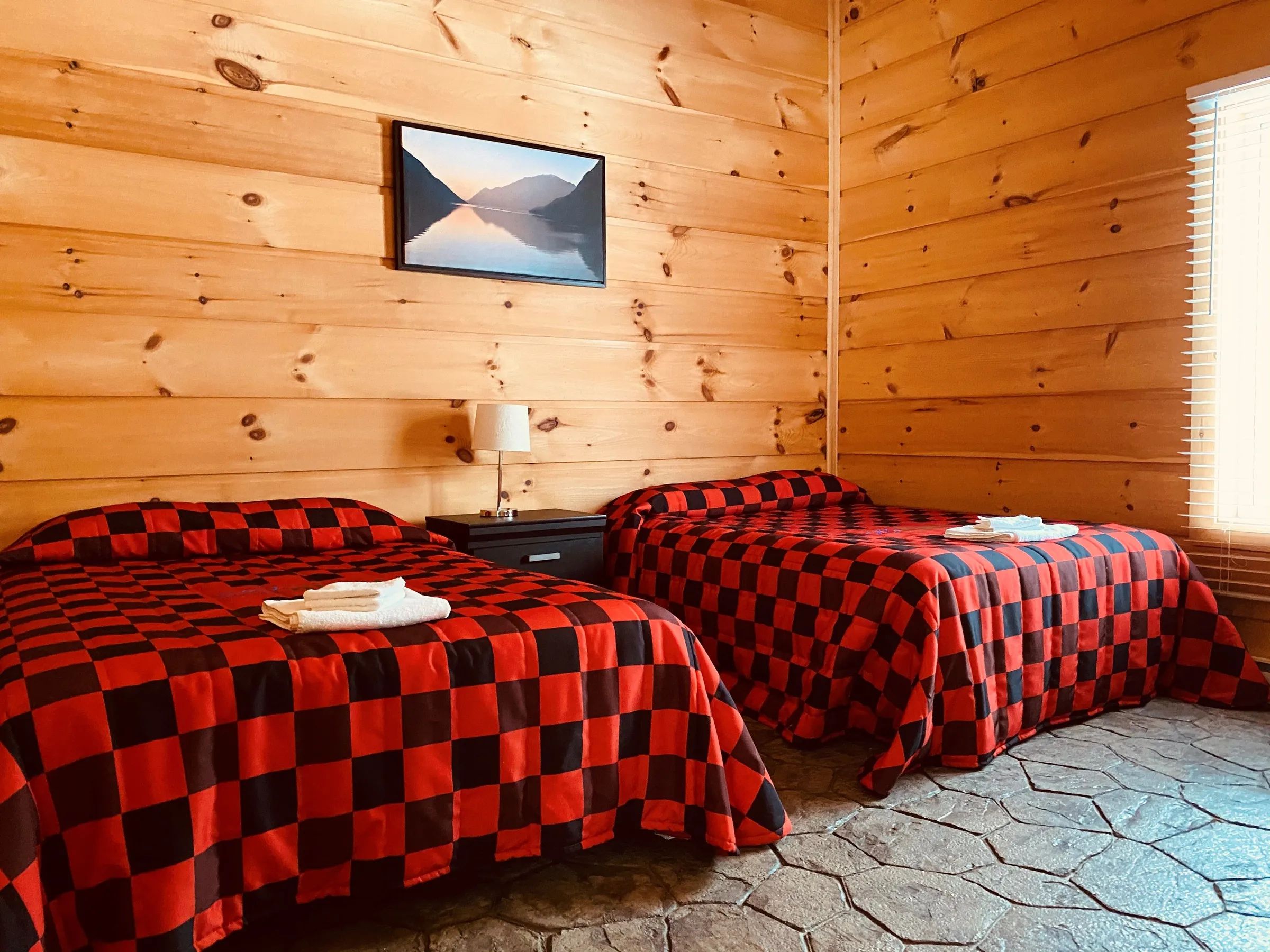 Cette chambre de chalet dispose de deux lits recouverts de jetés à motifs carreautés rouge et noir.