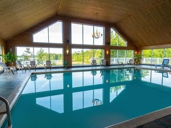 The indoor pool surrounded by large windows offers a view of the surrounding forest.