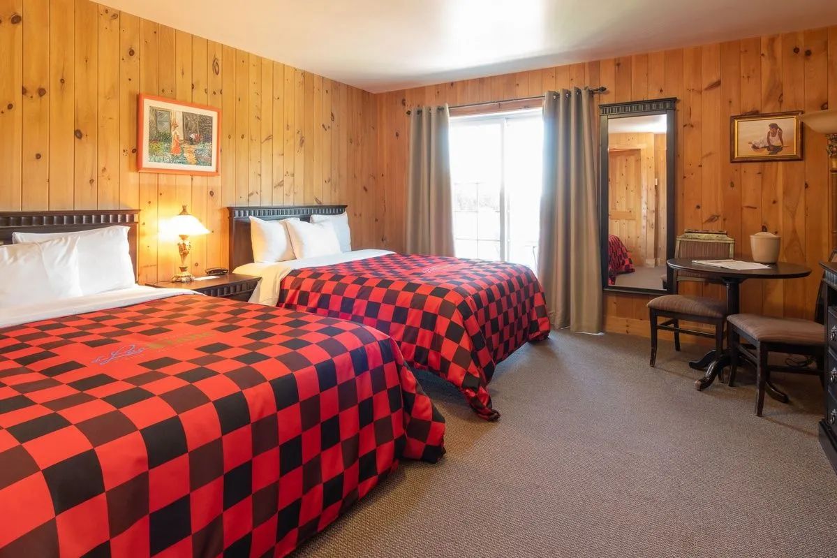 This room features two beds with red and black checkered bedspreads.