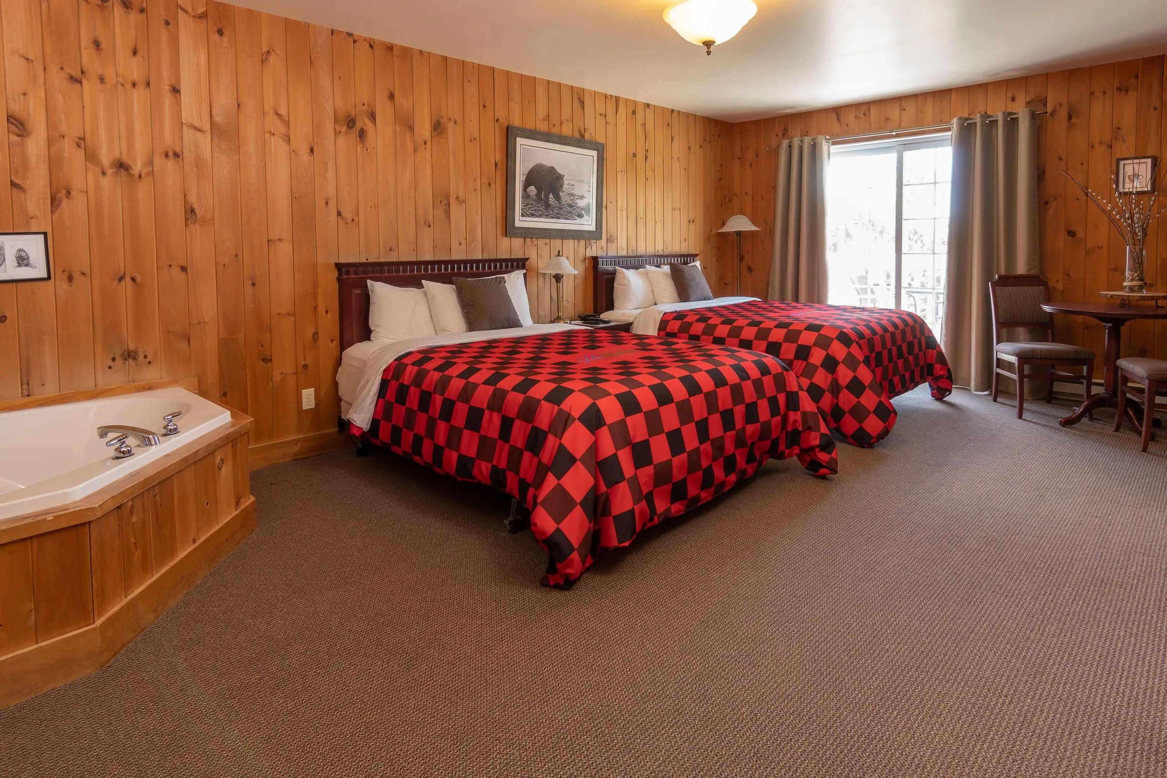 Cette chambre supérieure propose deux lits et une baignoire intégrée dans un décor en bois chaleureux.