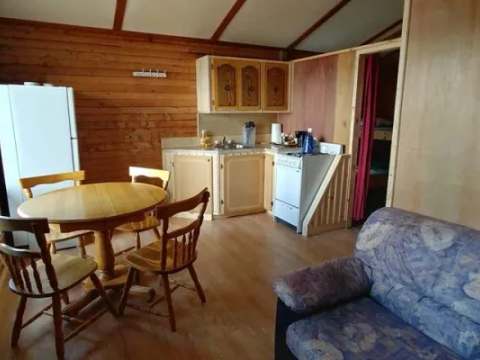 Vue d'ensemble de l'aire ouverte comprenant la cuisine, la table à manger et le coin salon du chalet.
