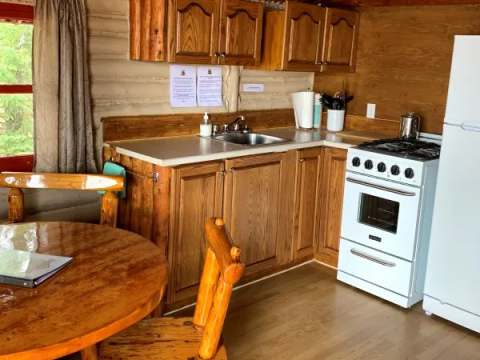 The functional kitchen in the Mésange cottage includes a stove, refrigerator, and a dining table.