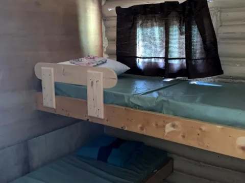 The Mésange cabin bedroom is equipped with wooden bunk beds.