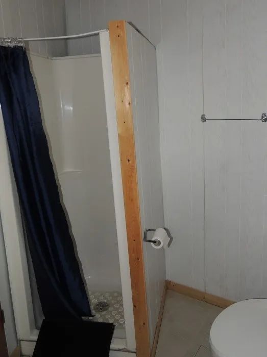 This cottage bathroom features a functional shower with a blue curtain.