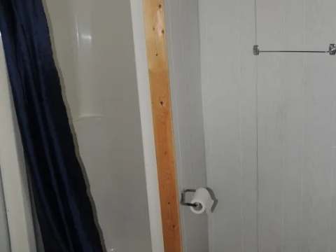 This cottage bathroom features a functional shower with a blue curtain.